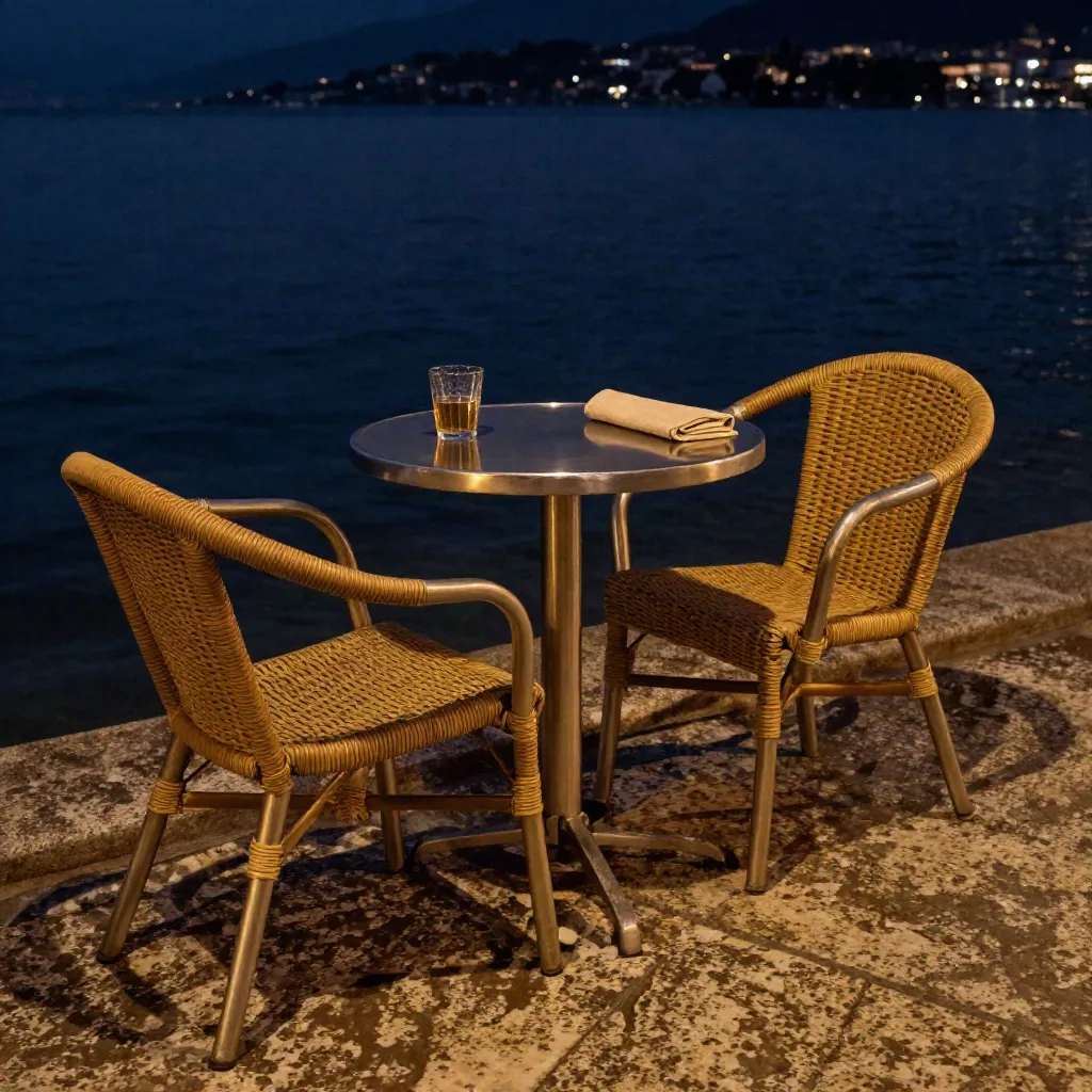 Abendliche Seeterrasse in Ascona mit leeren Stühlen, Tisch und dunklem Wasser.